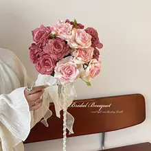 花嫁の手に持った花束、焦げた縁のバラの造花