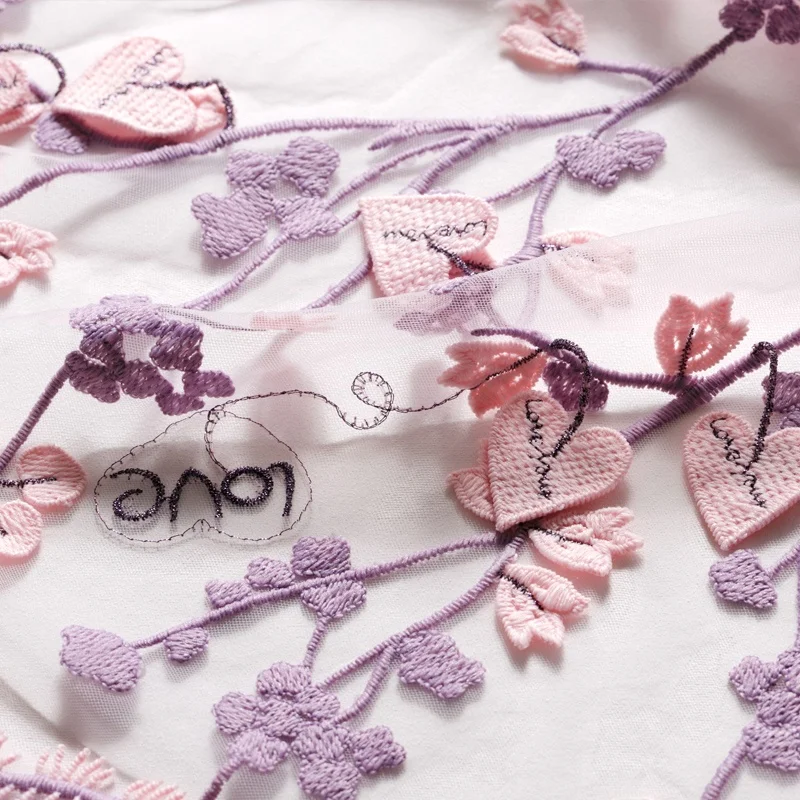 ピンクの刺繍入りメッシュレース生地：立体的なLOVE刺繍が柔らかさと透け感を実現