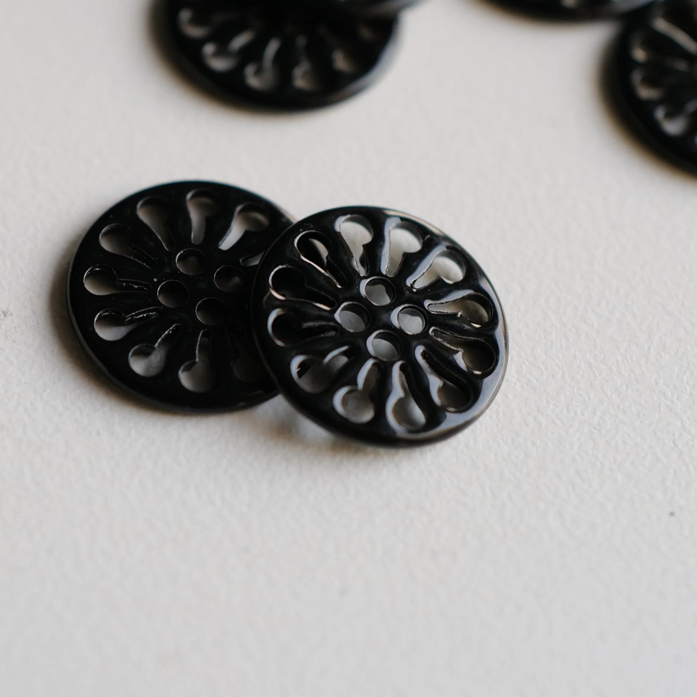 黒塗装の透かしデザイン金属ボタン【花輪形・ショート18mm】とは？